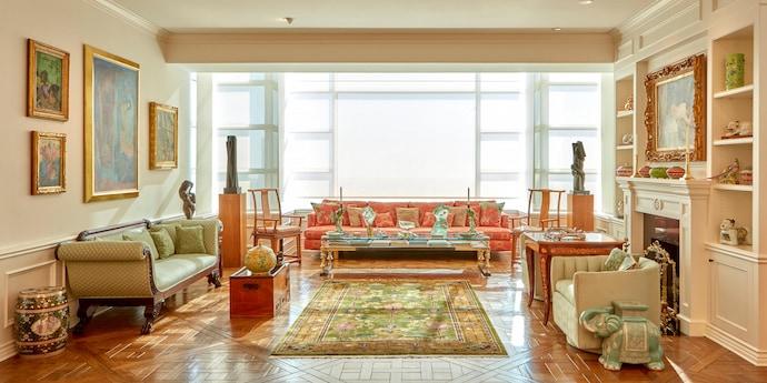 A room with a large, sunny window is filled with paintings, sculptures, antique furniture and Asian works of art.